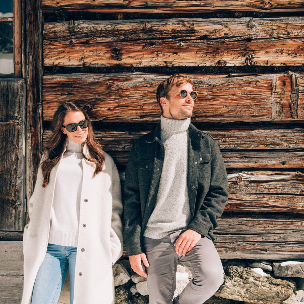 Couple relaxed in front of rustic wooden house at Hotel Post Lech