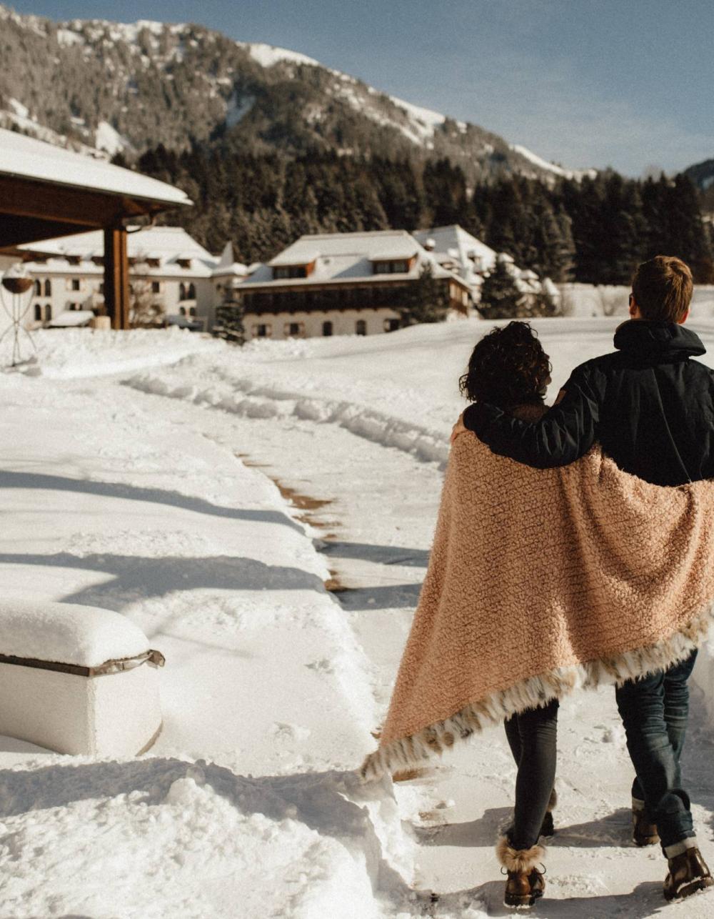 Coppia nella neve davanti allo Schlosshotel Kitzbühel, con le montagne sullo sfondo