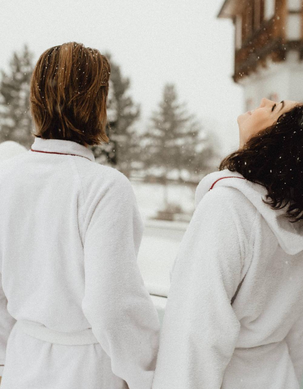 Paar im Bademantel auf Balkon im Schnee im Schlosshotel Kitzbühel