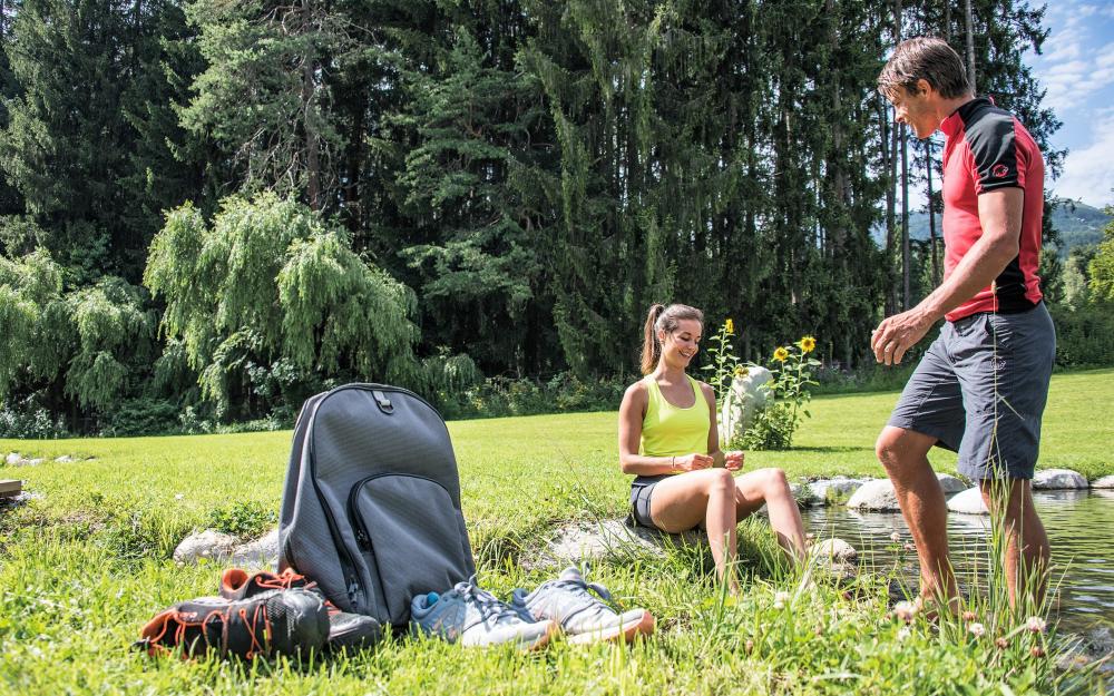 Hotel Weiher Gäste entspannen am Weiher mit Wander- und Sportschuhen im Gras