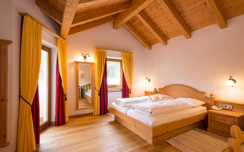 Gemütliches Hotelzimmer im Hotel Weiher mit Holzdecke und gelben Vorhängen