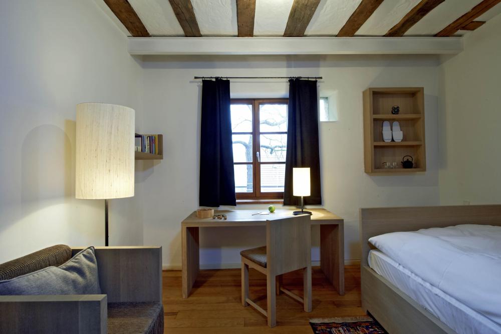 Einfaches Zimmer mit Schreibtisch und Bett im Kloster Hornbach