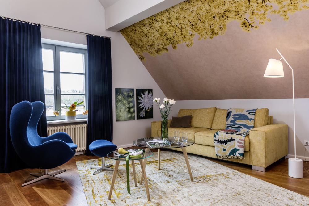 Helles Gästezimmer mit grünem Sessel und Bett im Kloster Hornbach