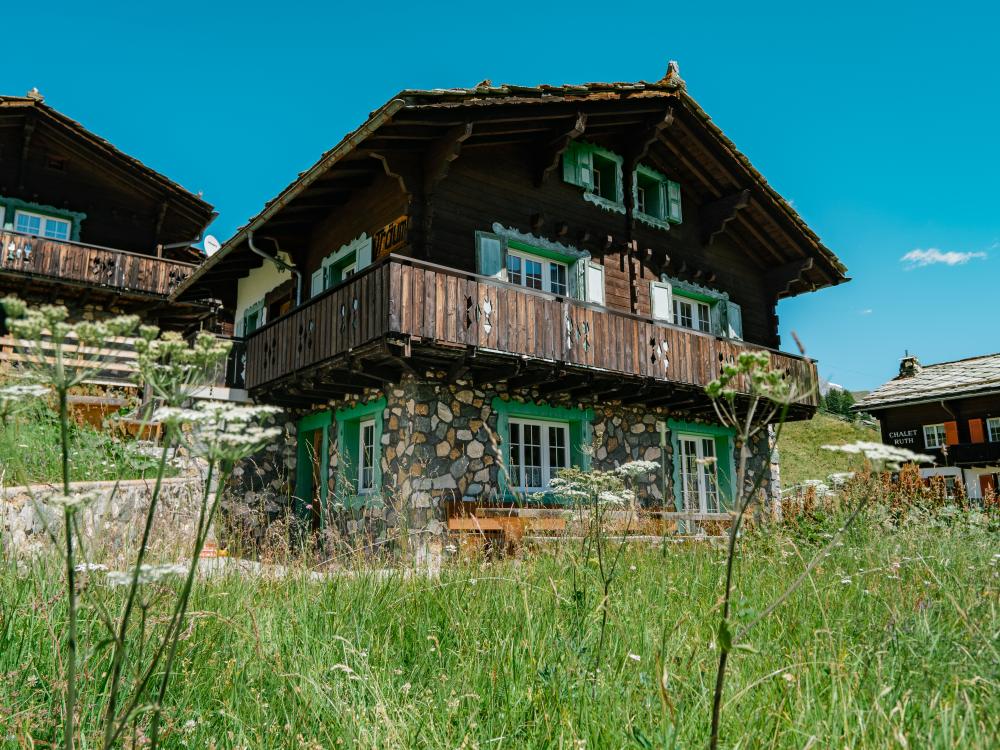 Resort La Ginabelle Zermatt mit traditionellen Chalets und grüner Wiese im Sommer