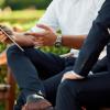 Zwei Männer sitzen draußen und besprechen Pläne mit Tablet im Hotel MOHR life resort