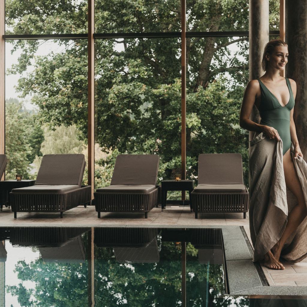 Frau am Pool mit Blick auf Bäume im Eibl-Brunner Spa-Bereich