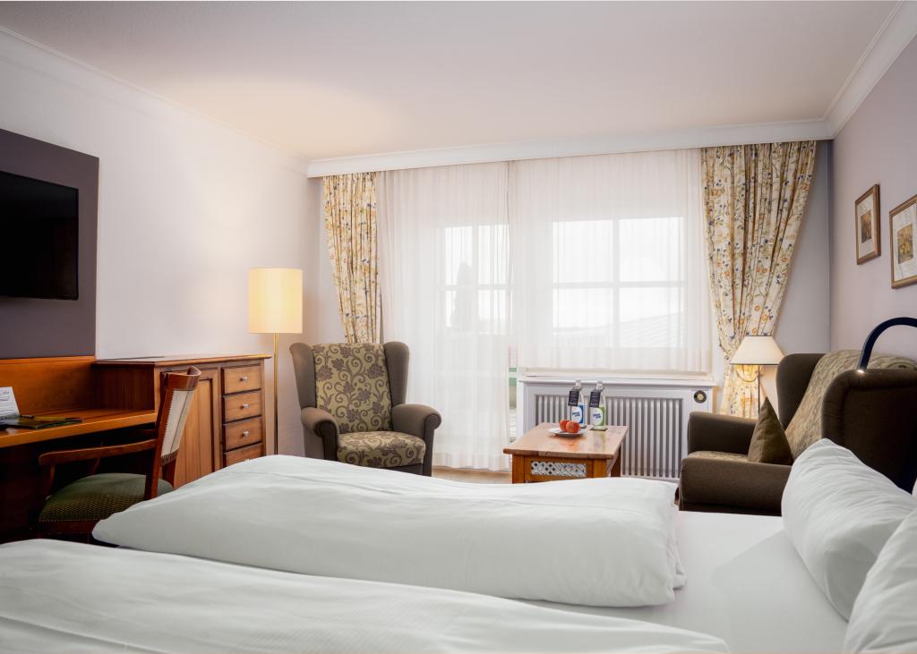 Gemütliches Zimmer im Sport- und Wellnesshotel Angerhof ****S mit Bett und Sitzbereich