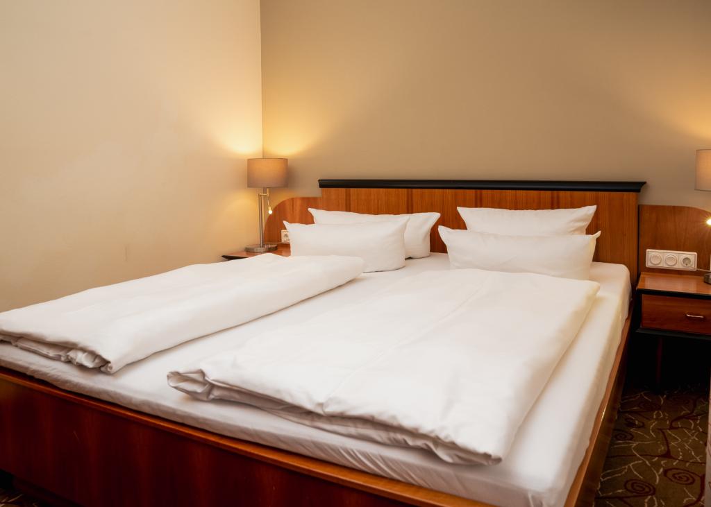 Doppelzimmer im Sport- und Wellnesshotel Angerhof ****S mit Holzbett und weißen Kissen
