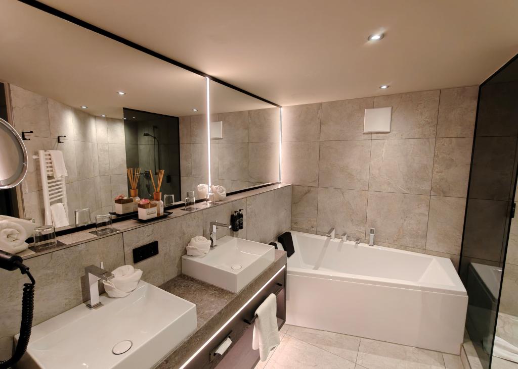 Modernes Badezimmer im Sport- und Wellnesshotel Angerhof ****S mit Badewanne und Doppelwaschbecken.
