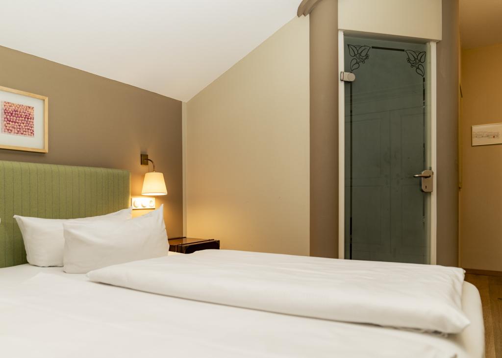 Gemütliches Zimmer im Sport- und Wellnesshotel Angerhof ****S mit grünem Kopfteil und Beleuchtung