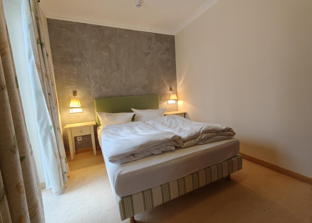 Modernes Doppelzimmer im Sport- und Wellnesshotel Angerhof ****S mit grüner Wand und Fenster