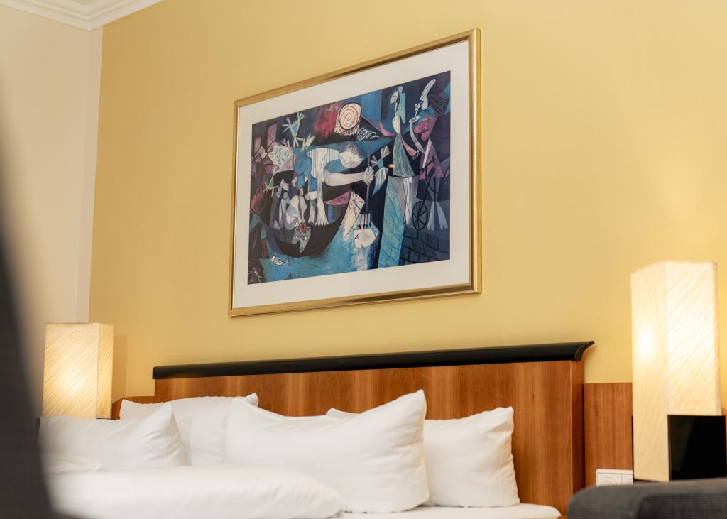 Wohnliches Zimmer mit Kunst über dem Bett im Sport- und Wellnesshotel Angerhof ****S