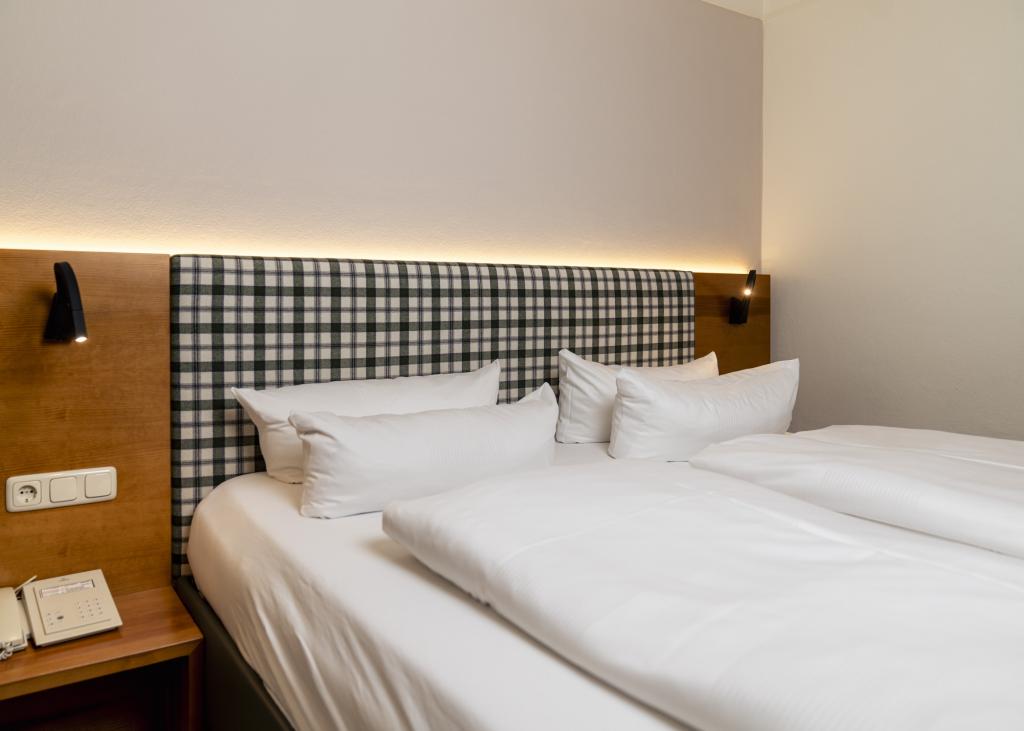 Gemütliches Bett mit kariertem Kopfteil im Sport- und Wellnesshotel Angerhof ****S