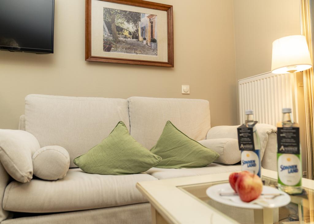 Gemütliche Sitzecke mit hellen Sofas und grünen Kissen im Sport- und Wellnesshotel Angerhof ****S.