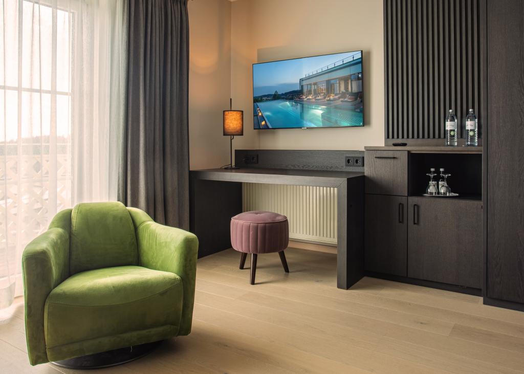 Modernes Zimmer im Sport- und Wellnesshotel Angerhof ****S mit grünem Sessel und TV