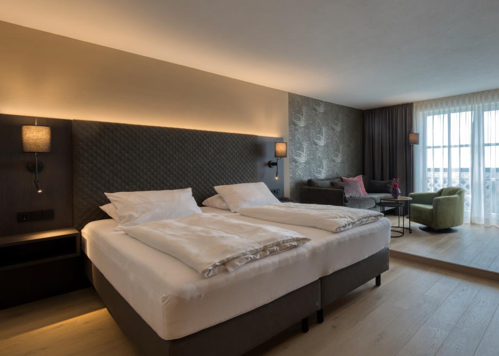 Modernes Schlafzimmer im Sport- und Wellnesshotel Angerhof ****S mit Doppelbett und Sitzbereich