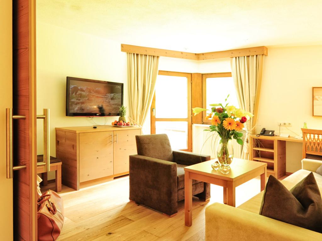 Helles Zimmer im Hotel Salnerhof mit Sitzbereich, Fenster und Blumen