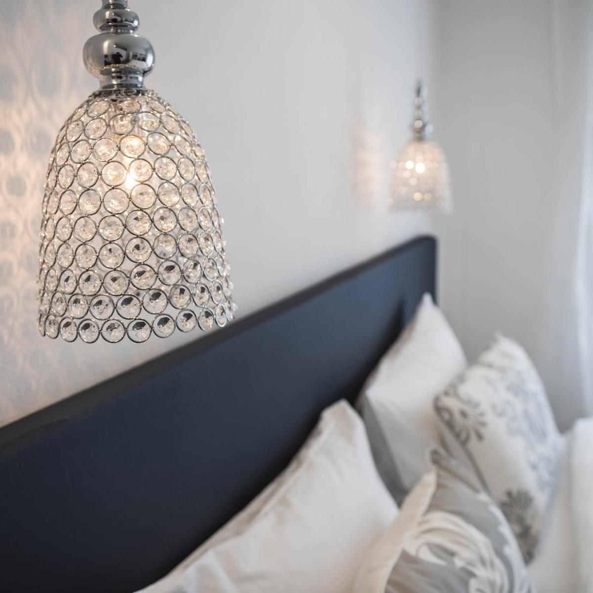 Stilvolles Schlafzimmer mit Pendelleuchten und dekorativen Kissen.