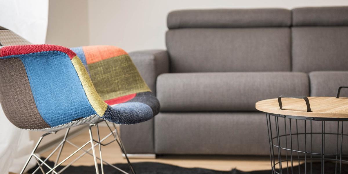 Brandnamic Wohnzimmer mit buntem Sessel, grauem Sofa und rundem Couchtisch
