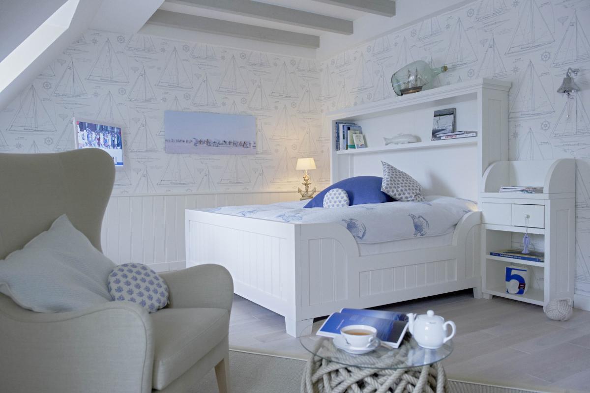 Lösch ruhiges helles Schlafzimmer mit weißem Bett, Stuhl und nautischem Dekor