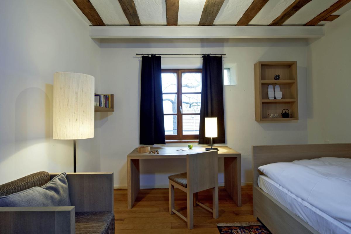 Einfaches Zimmer mit Schreibtisch und Bett im Kloster Hornbach