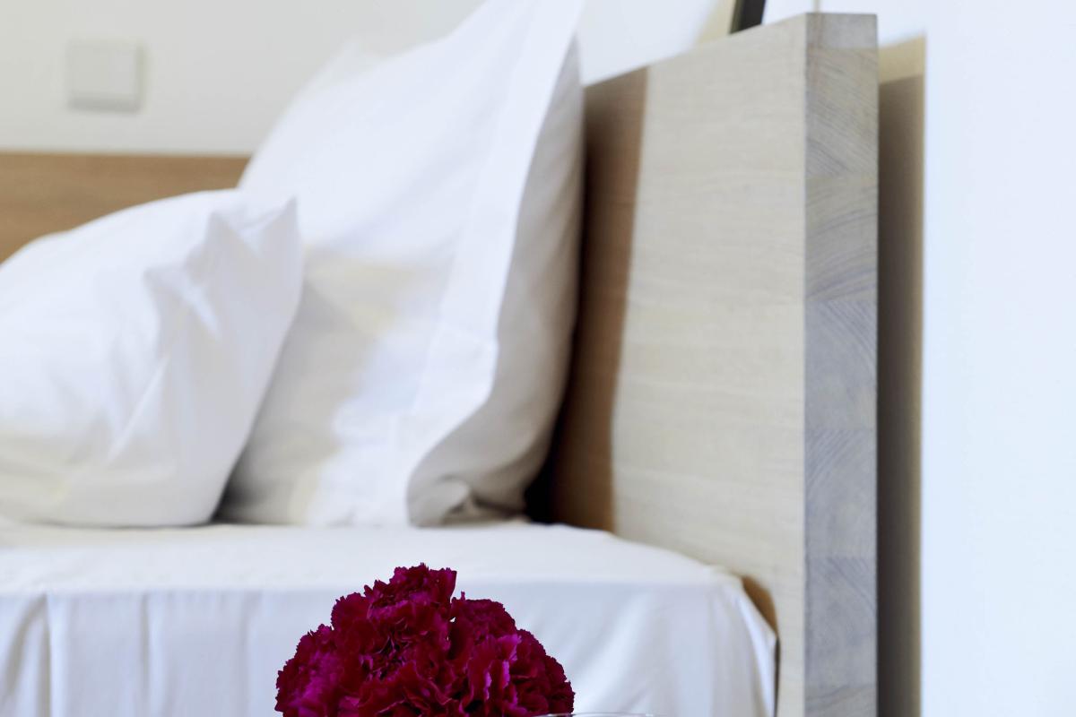 Schlichtes Zimmer im Kloster Hornbach mit Kreuz, Rosen und Buch auf Nachttisch