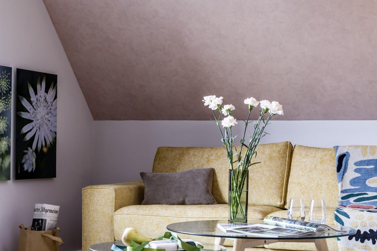 Gemütlicher Wohnbereich im Kloster Hornbach mit gelbem Sofa und Glas-Tischen