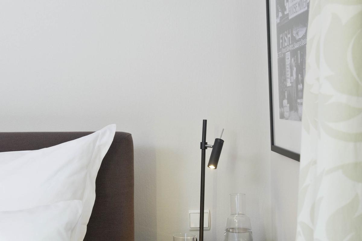 Schlafzimmer mit Bett und Lösch-förmigem Nachttisch mit Lampe