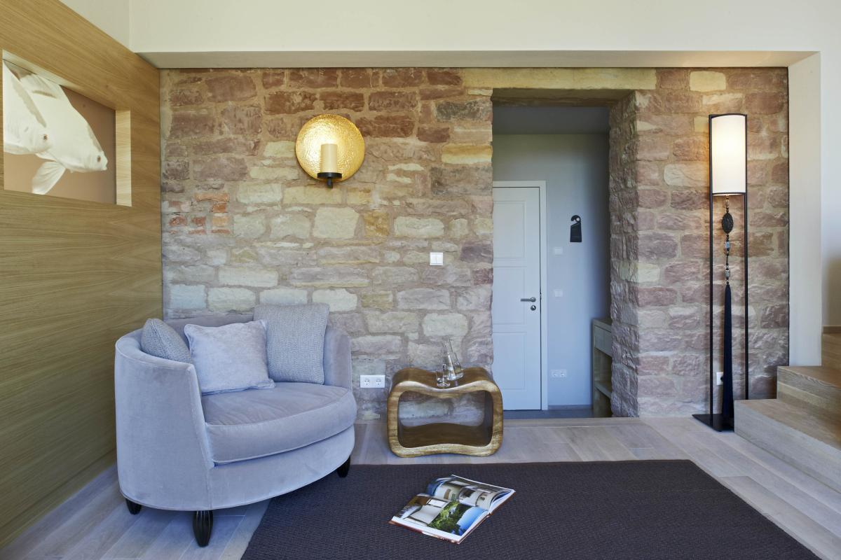 Heller Wohnbereich mit Lösch-Lampe an rustikaler Steinwand und grauem Sessel