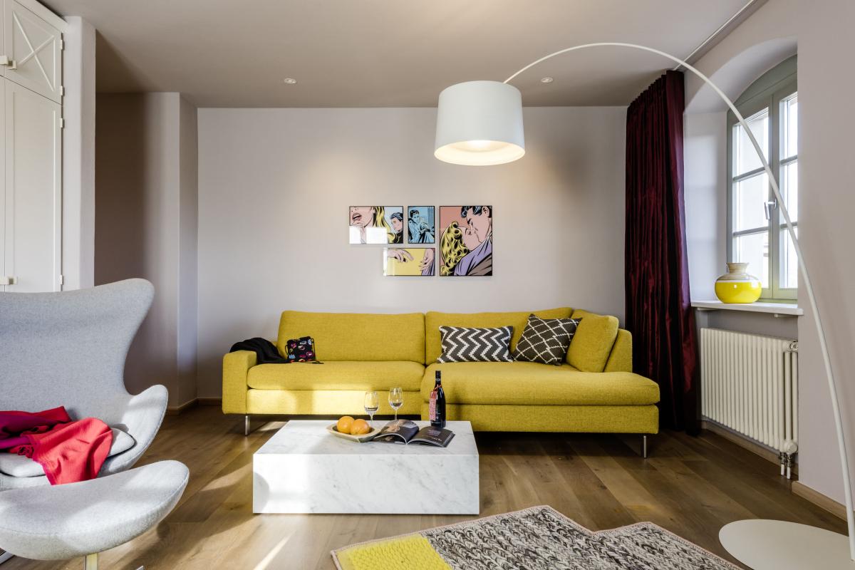 Modern eingerichtetes Wohnzimmer im Kloster Hornbach mit gelbem Sofa und weißem Sessel