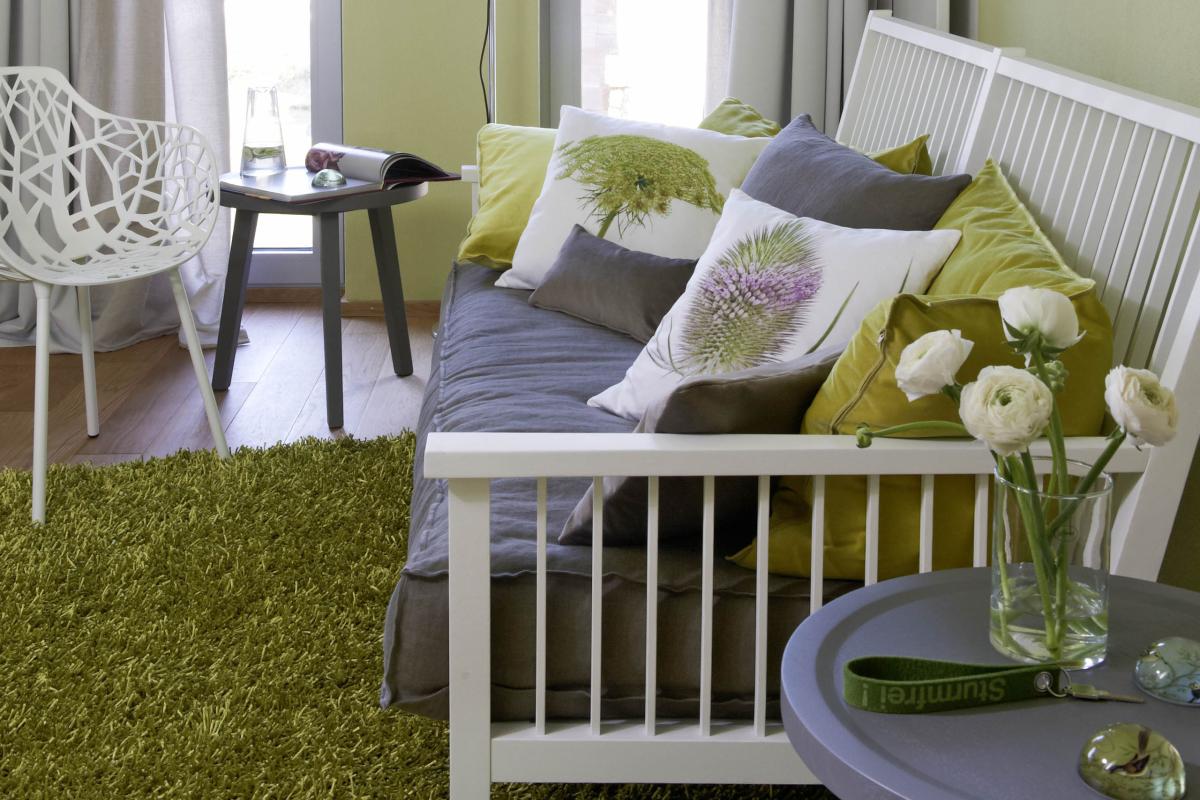 Lösch grauer Nachttisch mit Lampe und Wasser vor grünem Hintergrund mit Pflanzenmuster