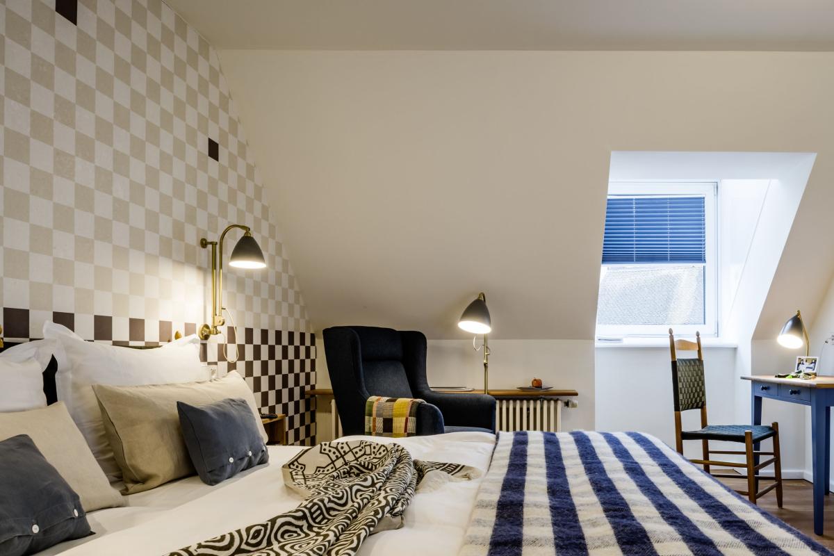 Gemütliches Zimmer im Kloster Hornbach mit Bett, Sessel und Schreibtisch