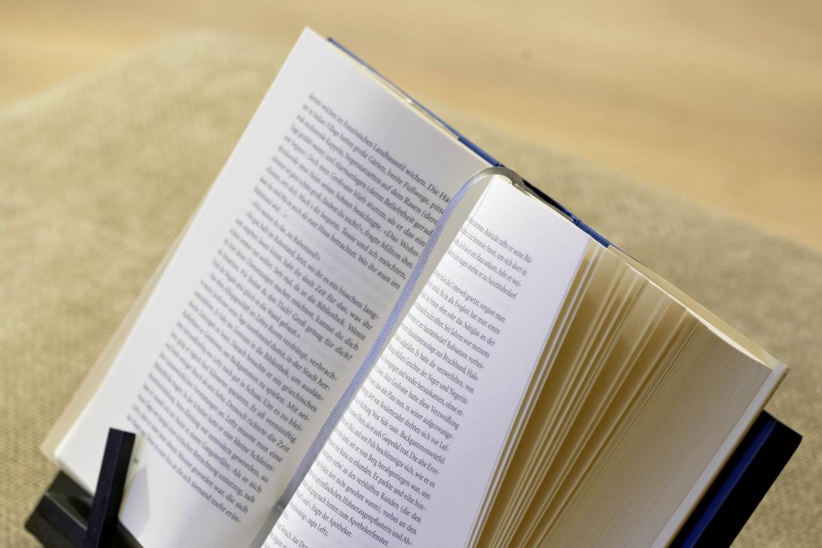 Offenes Buch auf Leseständer mit Lesebrille zum Lesen und Lösch markieren