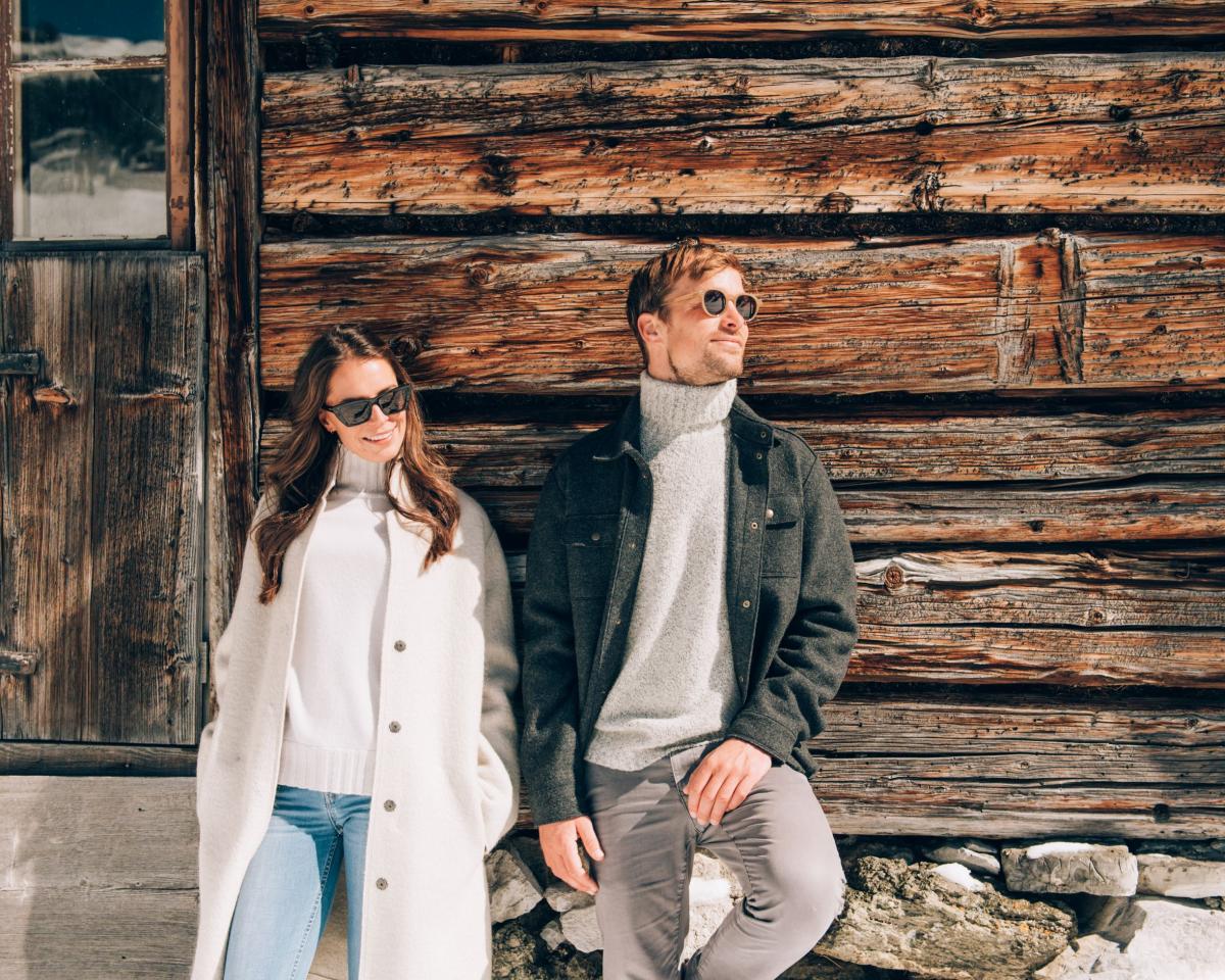 Couple relaxed in front of rustic wooden house at Hotel Post Lech