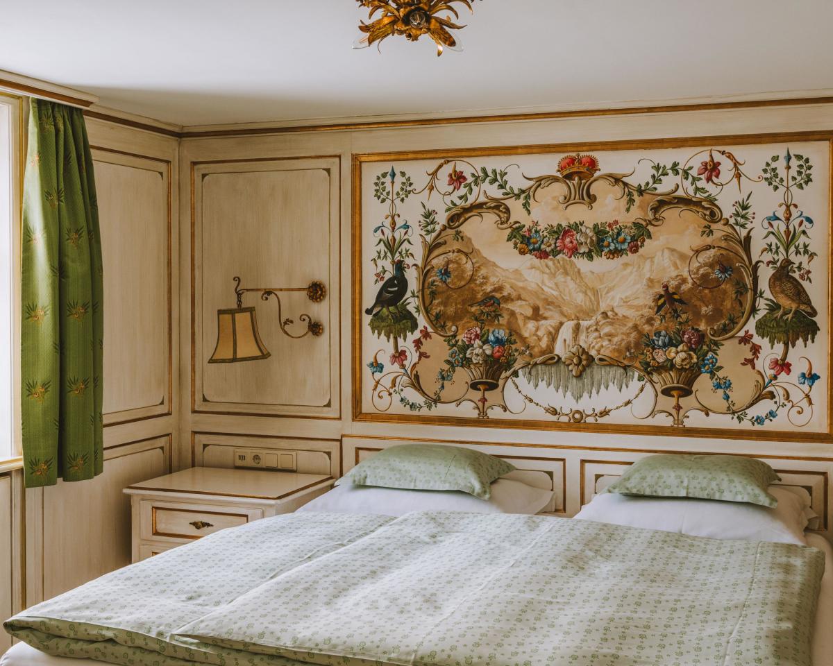 Bedroom at Hotel Post Lech with double bed and floral wall mural