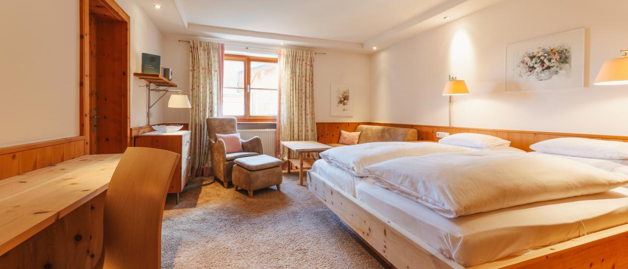 Hotel Aurora bedroom with a wooden bed, desk, seating area and window