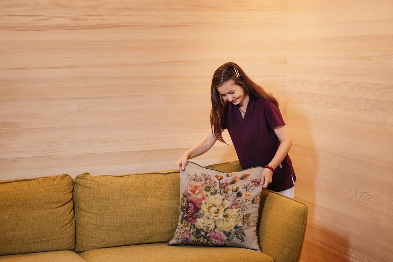 Hotel Aurora staff arranging floral cushion on yellow sofa
