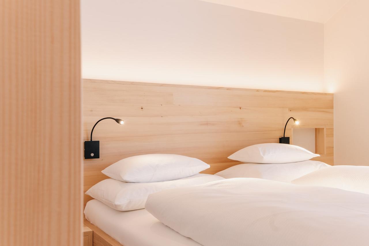 Bedroom with two beds at Hotel Aurora featuring light wood décor and reading lights