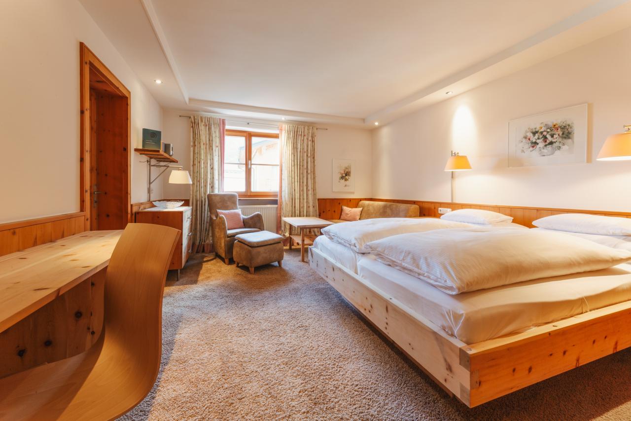 Hotel Aurora bedroom with a wooden bed, desk, seating area and window