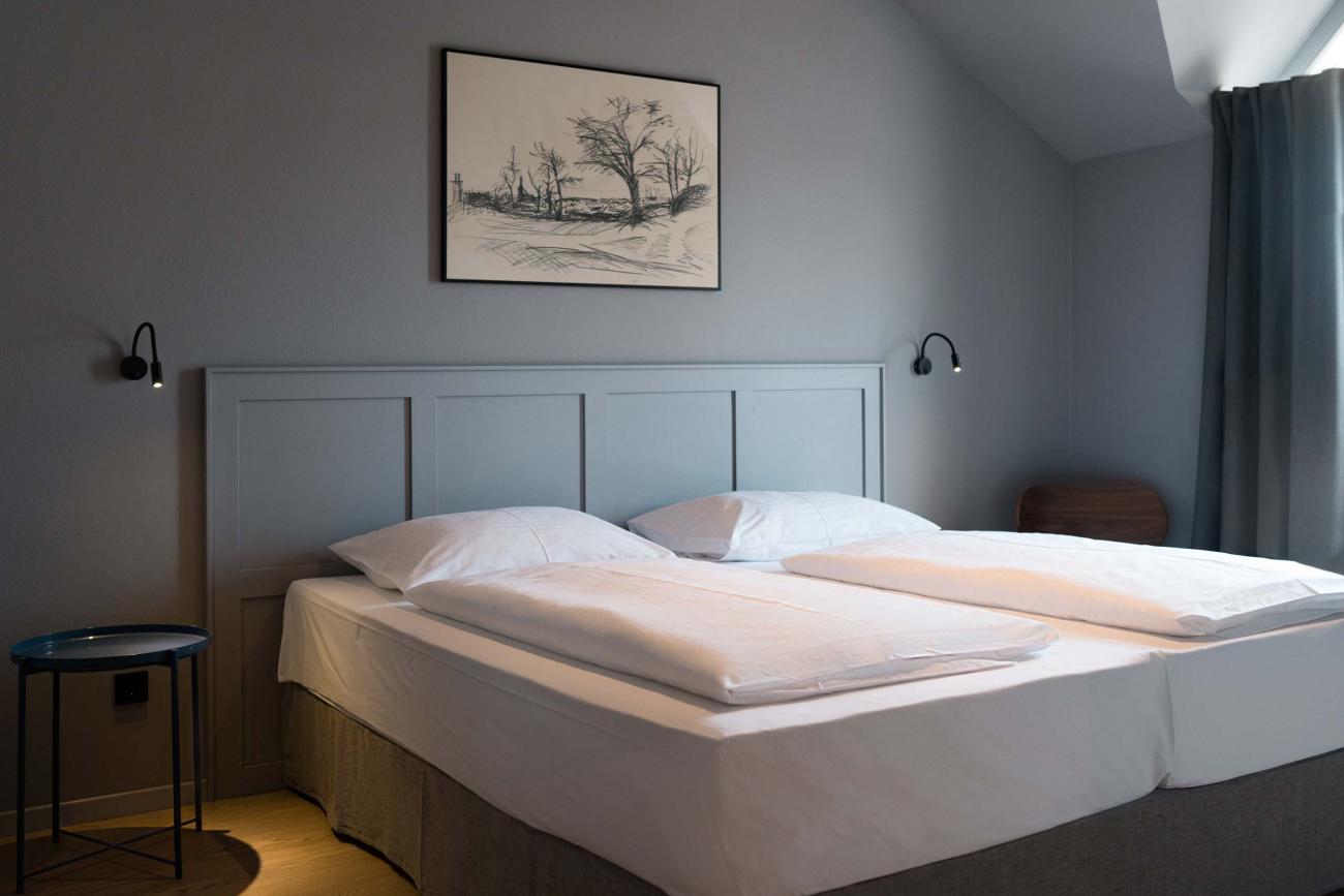 Schlichtes Schlafzimmer mit Doppelbett und Luis v. Weyden Kunst an der Wand