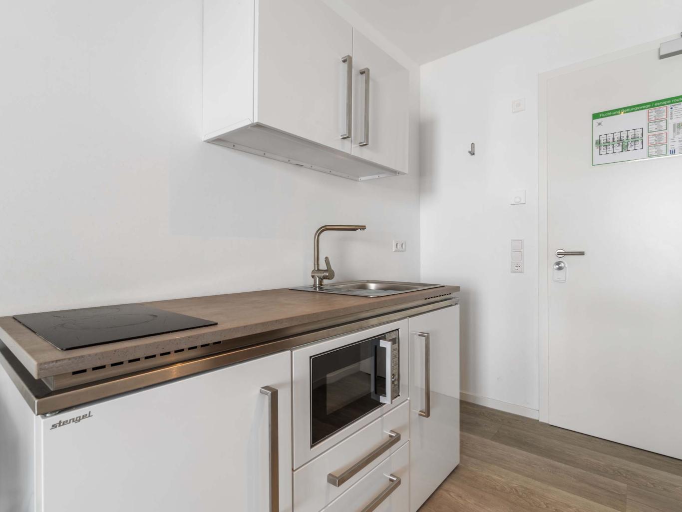 Moderne weiße Küche mit LIVINGBOXX® Schränken und Holzarbeitsplatte