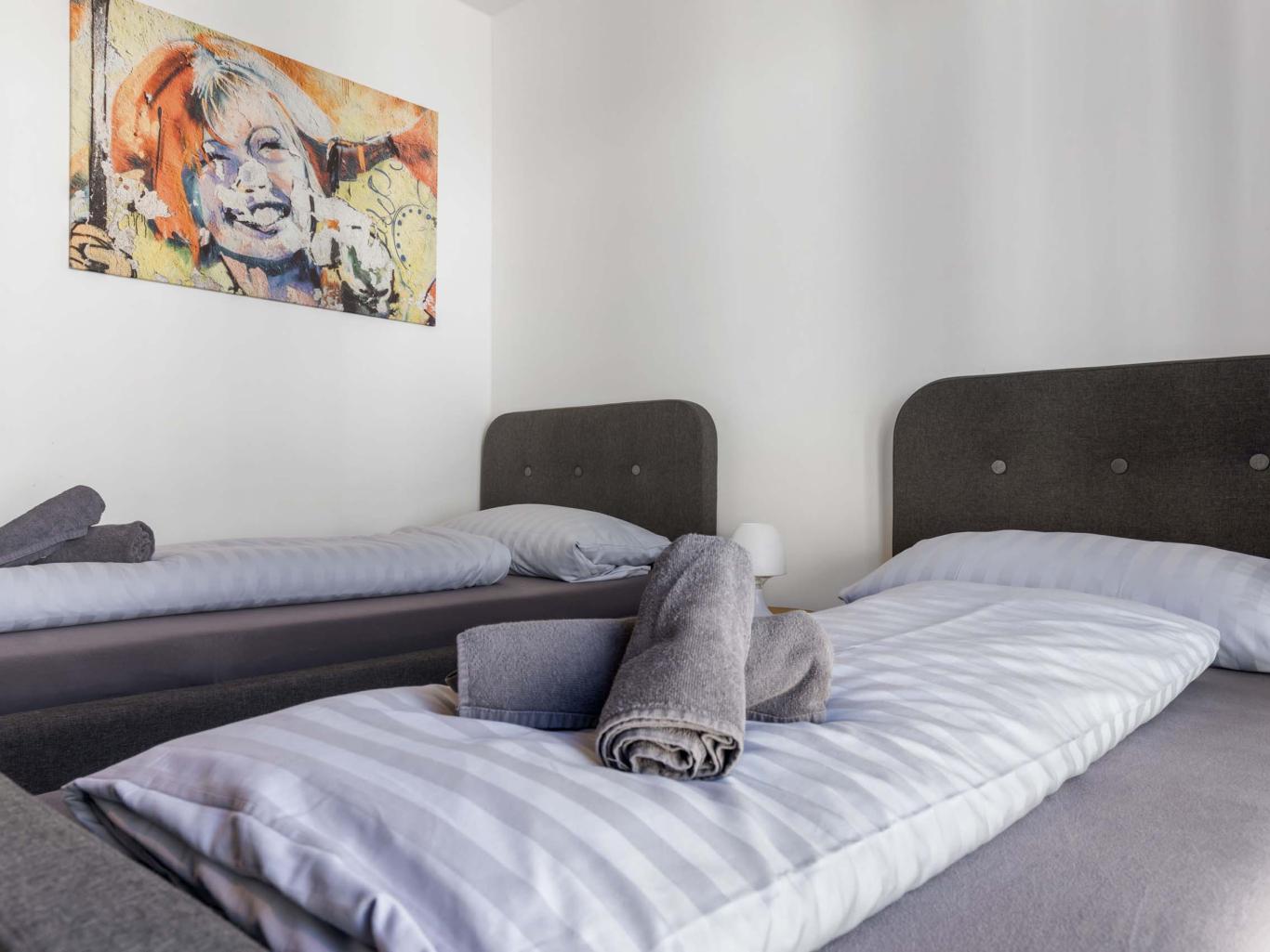 LIVINGBOXX® Schlafzimmer mit zwei Betten und moderner Kunst an der Wand