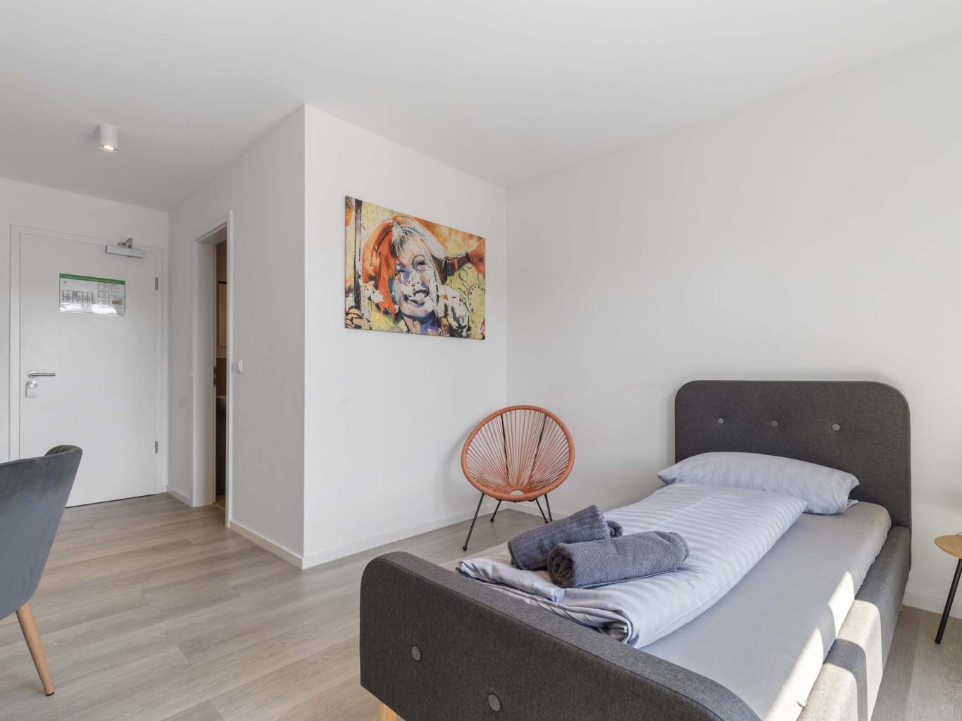 LIVINGBOXX® Zimmer mit Einzelbett, Stuhl und moderner Dekoration