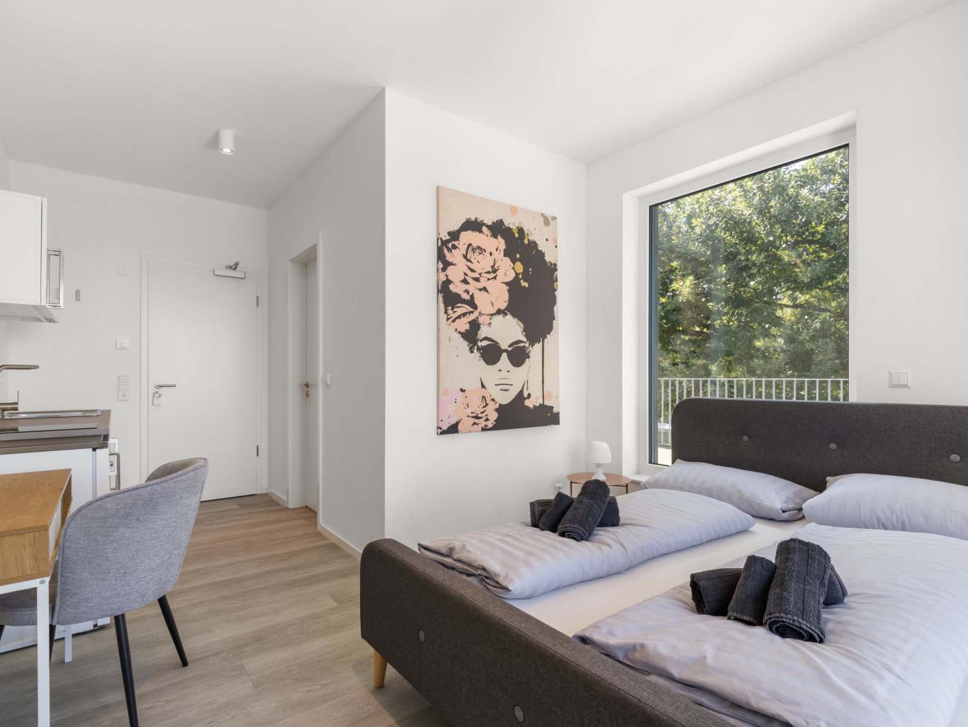 LIVINGBOXX® modernes Schlafzimmer mit Balkon und Küche in heller Wohnung