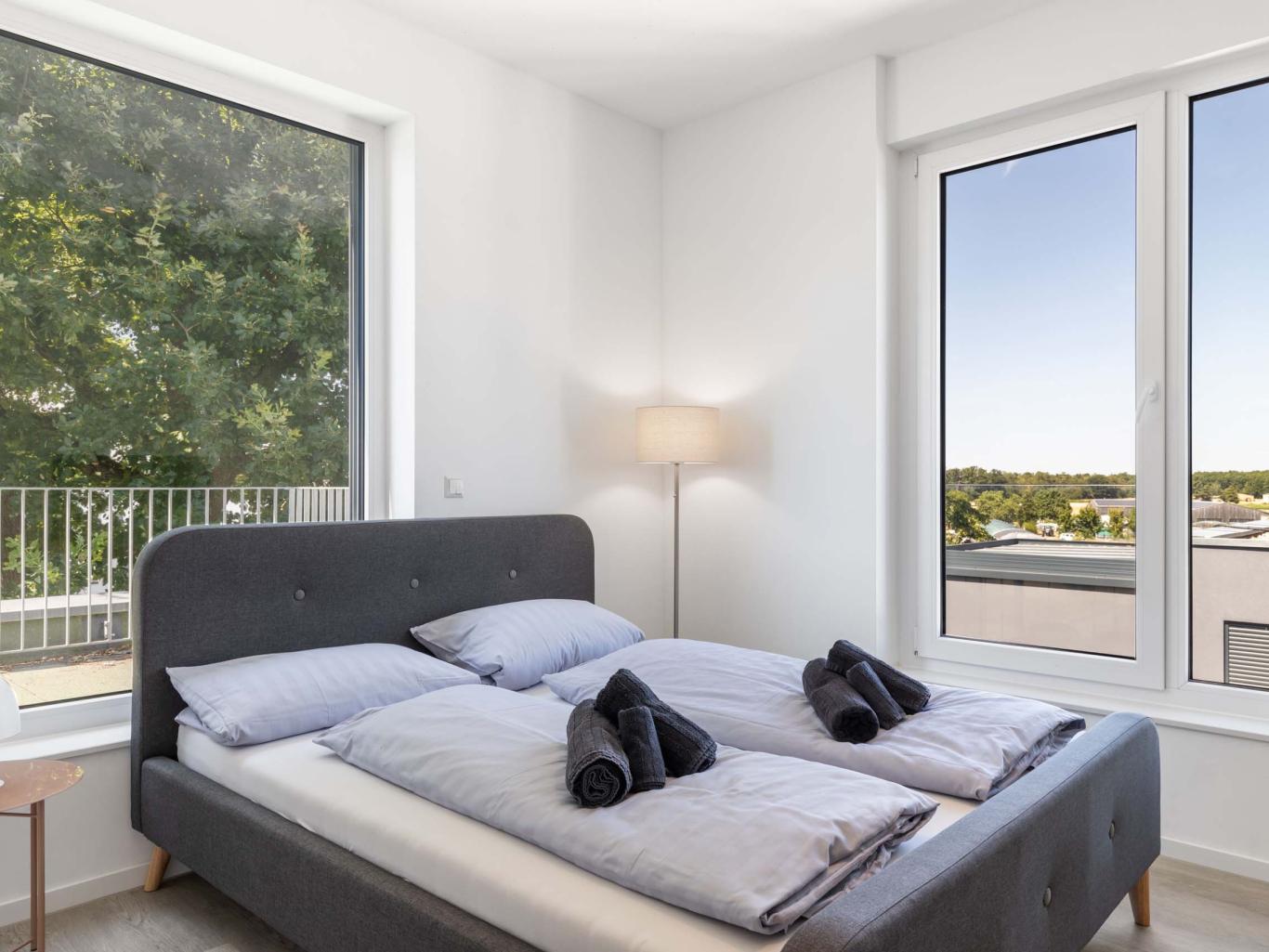 Modernes Schlafzimmer mit LIVINGBOXX® Fenstern und Balkonblick