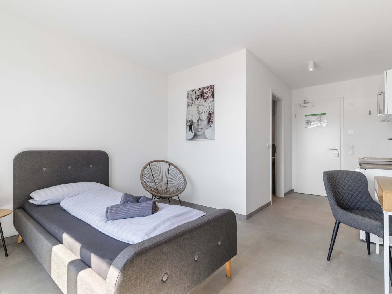 Modernes LIVINGBOXX® Apartment mit Einzelbett und Küchenzeile in weißem Design