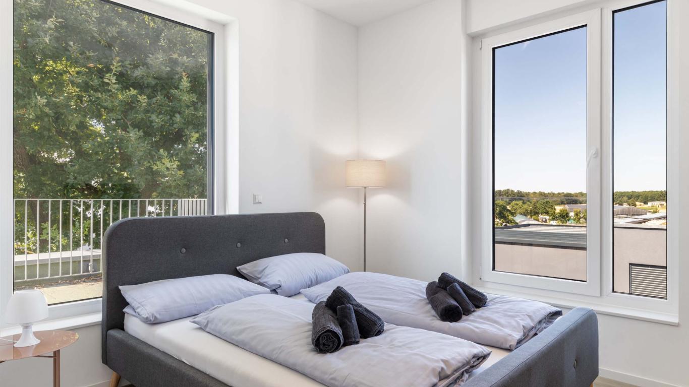 Modernes Schlafzimmer mit LIVINGBOXX® Fenstern und Balkonblick