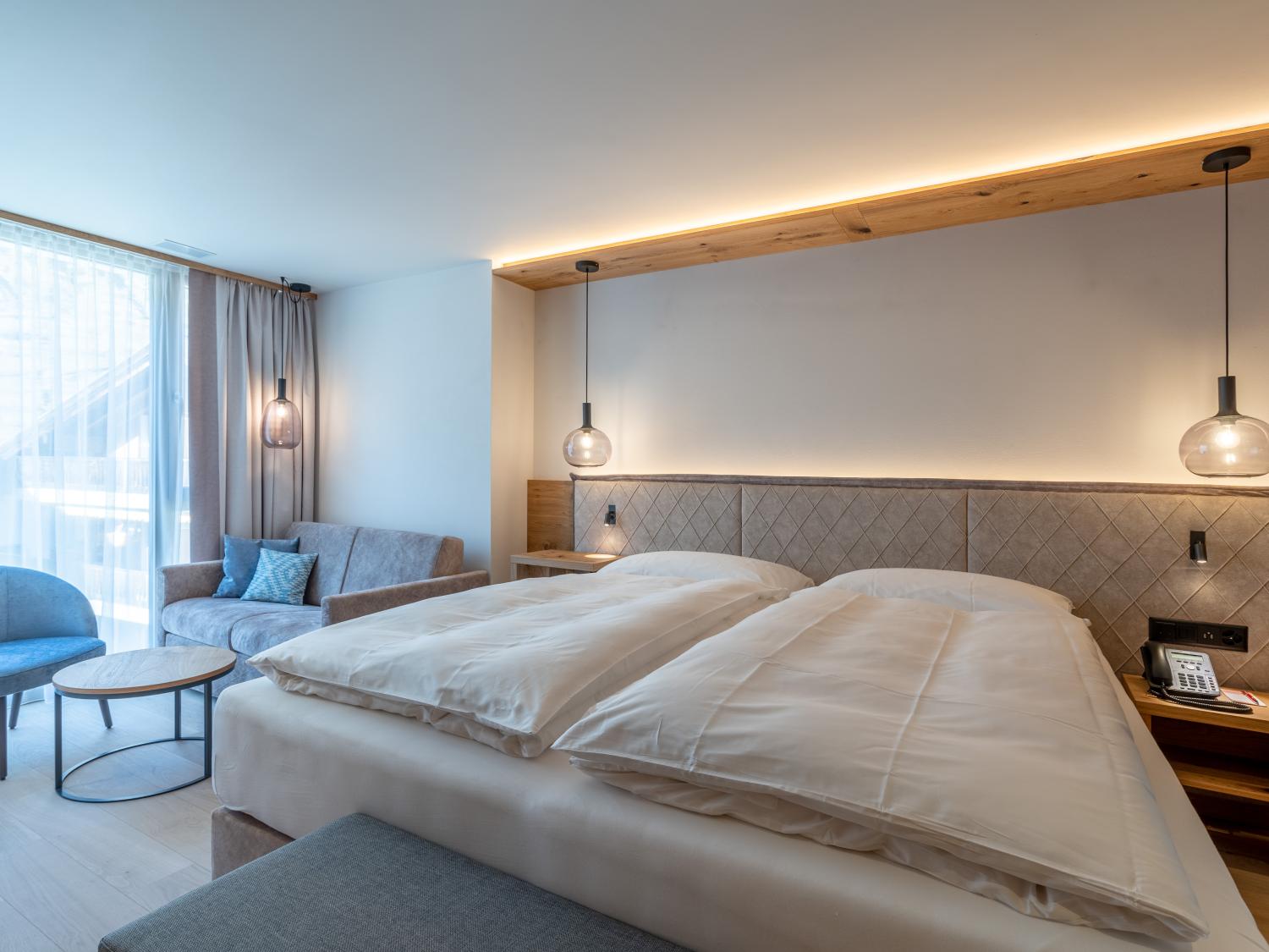 Gemütliches Schlafzimmer im Resort La Ginabelle Zermatt mit Doppelbett und Sitzecke