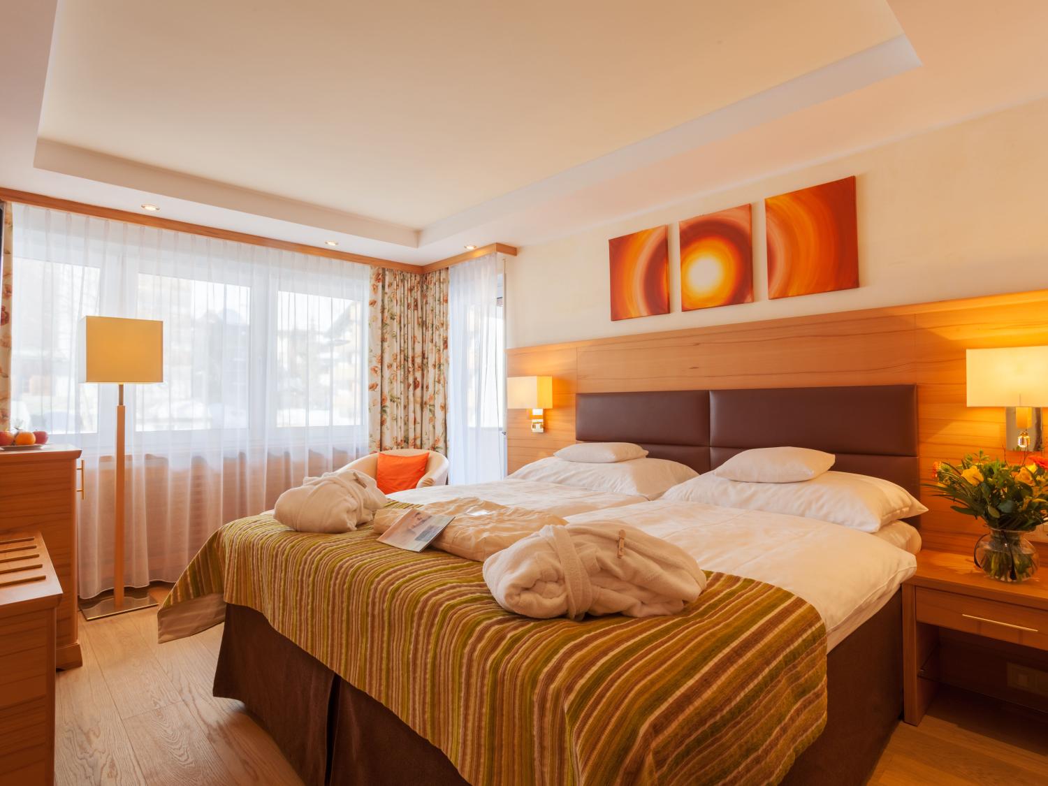 Gemütliches Zimmer im Resort La Ginabelle Zermatt mit Doppelbetten und warmem Licht