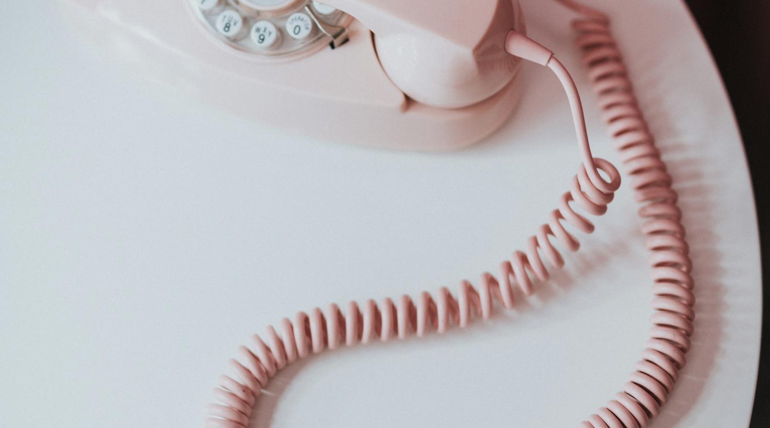Rosa Wählscheibentelefon mit Glockna auf weißem Tisch